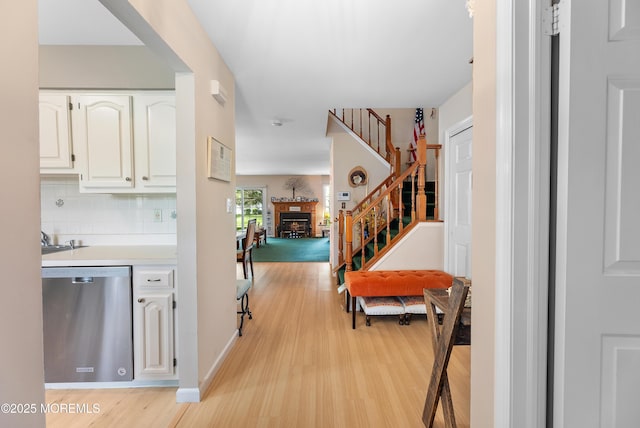 hallway with light wood-style floors, stairs, and baseboards