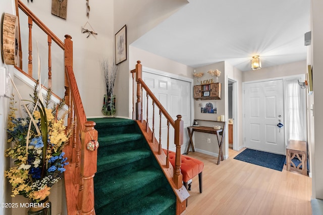 foyer featuring baseboards, stairs, and light wood finished floors
