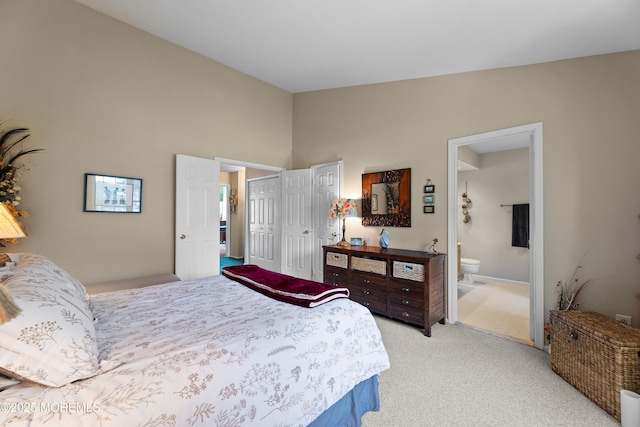 bedroom with light colored carpet, a towering ceiling, and ensuite bathroom