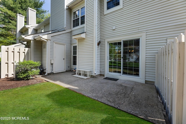 rear view of property featuring fence, a patio, and a chimney