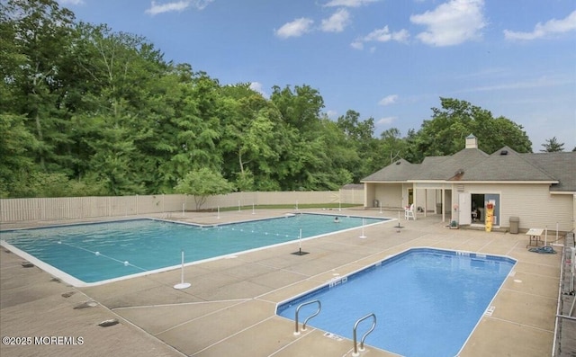 community pool with a patio area and fence