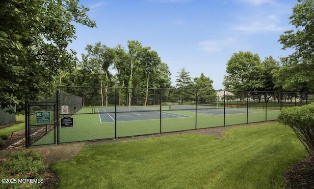 view of tennis court with fence and a yard