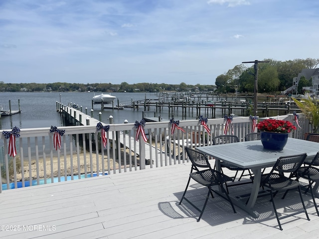 wooden deck with a water view, outdoor dining area, and a boat dock