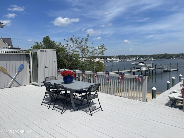 wooden deck featuring outdoor dining area, a water view, and a boat dock
