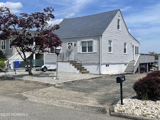 view of front of property with roof with shingles and stairway