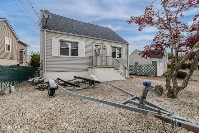 view of front of home with fence and roof with shingles