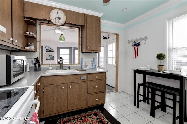 kitchen featuring brown cabinetry, range, a sink, light countertops, and stainless steel microwave