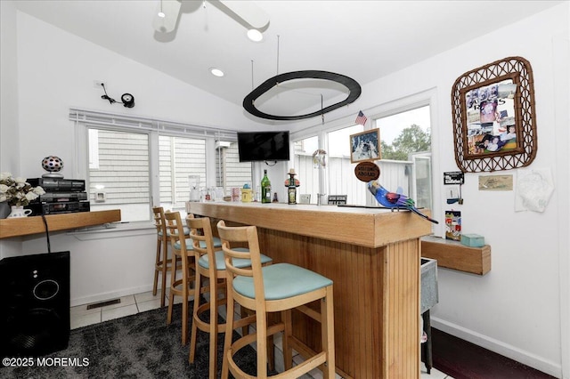 bar with a ceiling fan, lofted ceiling, baseboards, tile patterned floors, and a dry bar
