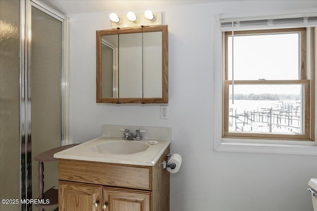 bathroom with toilet, a shower with door, and vanity