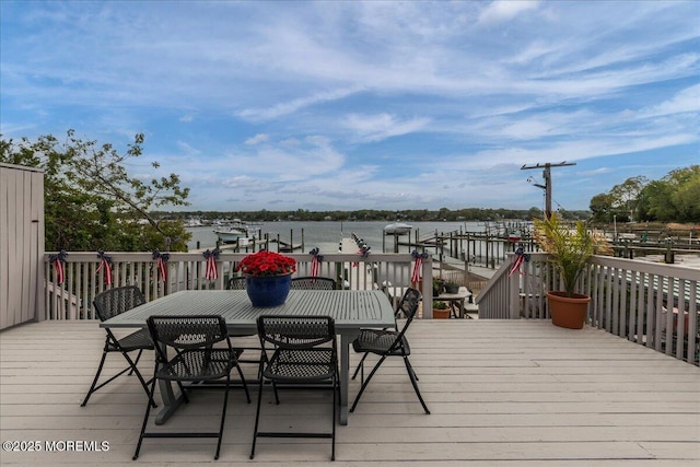 wooden deck with outdoor dining area and a water view