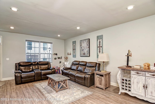 living room featuring recessed lighting, baseboards, and light wood-type flooring