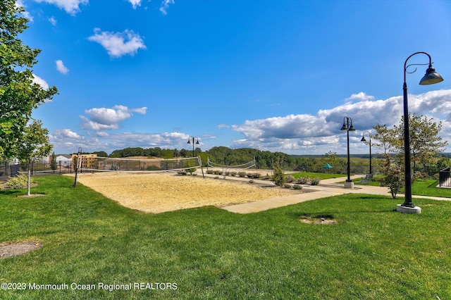 view of community with volleyball court, fence, and a lawn