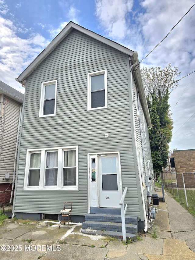 rear view of house with fence and entry steps