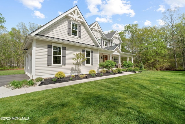 view of front facade with a front lawn, a porch, a standing seam roof, and metal roof