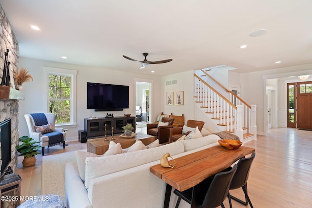 living room with stairway, light wood-type flooring, plenty of natural light, a ceiling fan, and recessed lighting