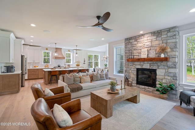 living area with light wood-style flooring, a fireplace, ceiling fan, and recessed lighting