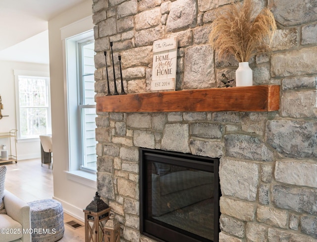 detailed view of a fireplace, wood finished floors, and baseboards