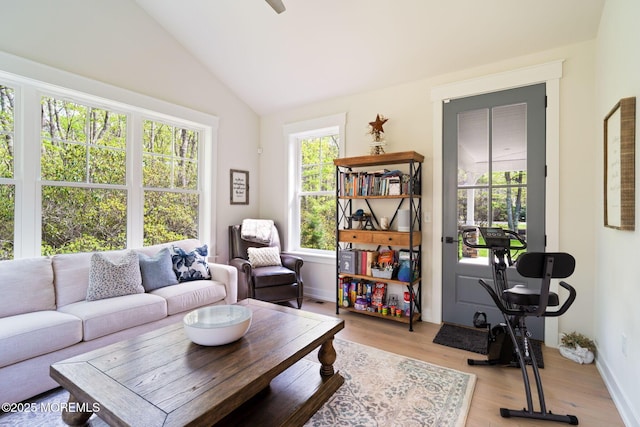 living area with vaulted ceiling, light wood-style flooring, and baseboards