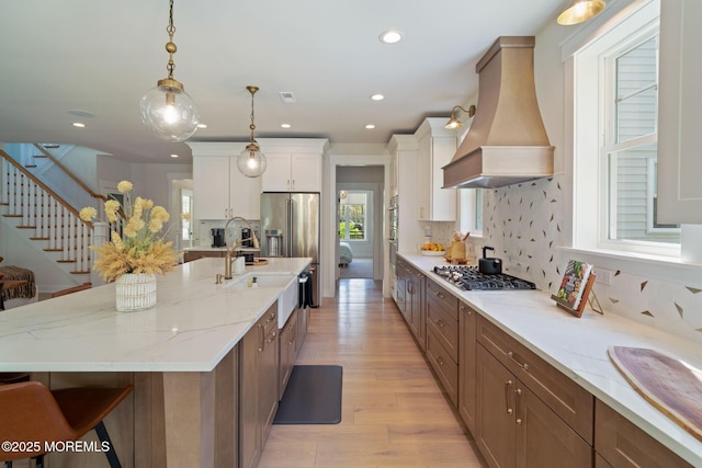 kitchen featuring premium range hood, stainless steel appliances, decorative backsplash, light wood-style flooring, and recessed lighting