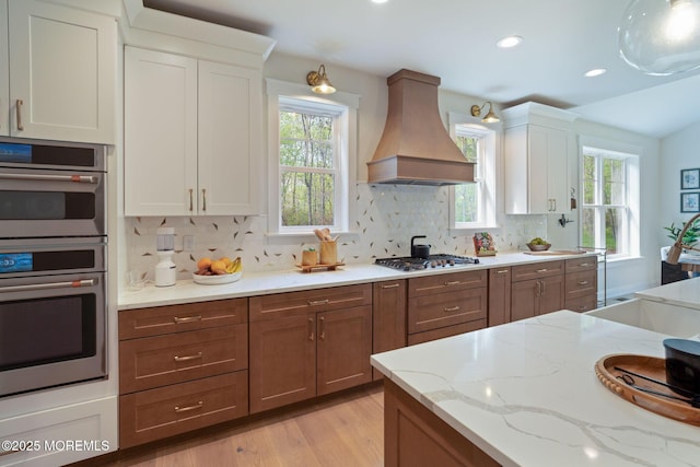 kitchen with custom range hood, appliances with stainless steel finishes, white cabinets, decorative backsplash, and recessed lighting