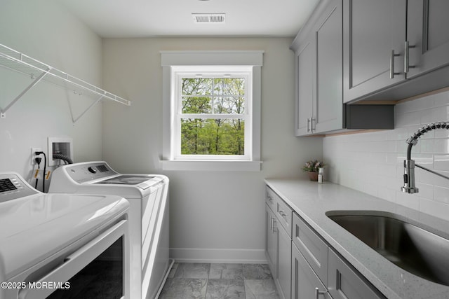 laundry area with cabinet space, washing machine and clothes dryer, light marble finish floors, and baseboards