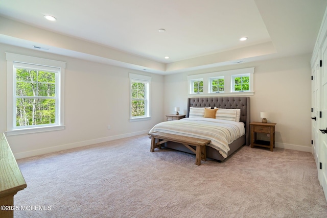 bedroom with baseboards, a tray ceiling, light carpet, and recessed lighting