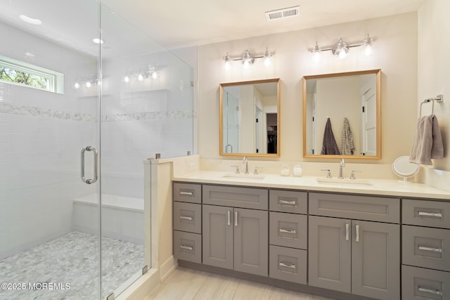 bathroom featuring a shower stall and double vanity