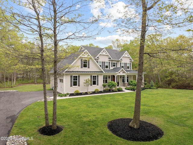 craftsman inspired home with a standing seam roof, covered porch, a front yard, metal roof, and asphalt driveway