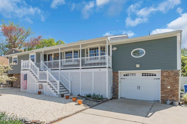 view of front of house with covered porch, driveway, an attached garage, stairs, and stone siding