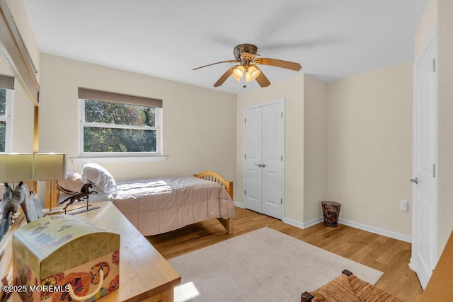 bedroom featuring light wood-style floors, baseboards, ceiling fan, and a closet