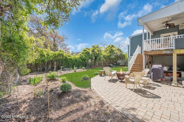 view of yard featuring fence, a ceiling fan, a patio area, an outdoor fire pit, and stairway