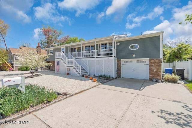view of front of property featuring covered porch, driveway, fence, an attached garage, and stairs