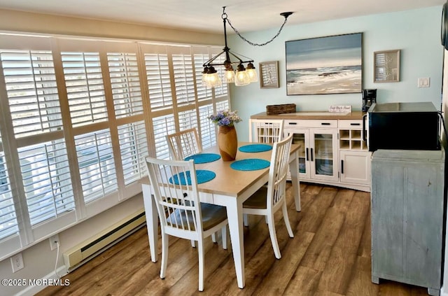 dining space with a chandelier, plenty of natural light, wood finished floors, and a baseboard radiator