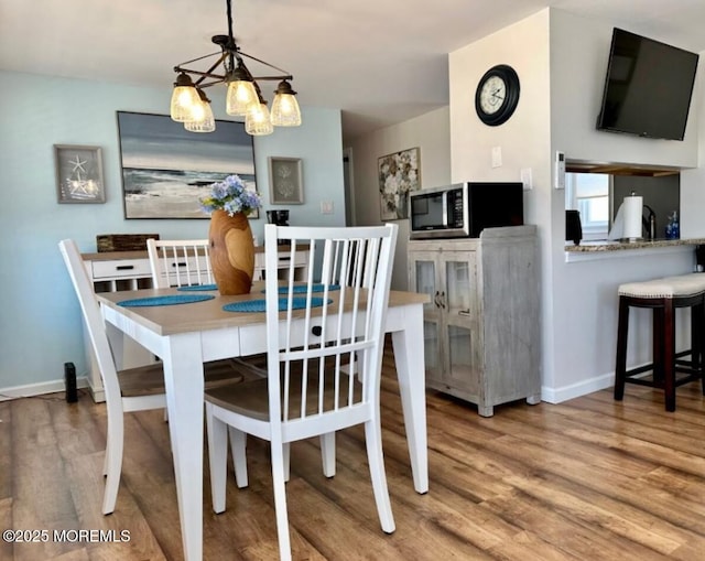 dining room with baseboards, wood finished floors, and a notable chandelier