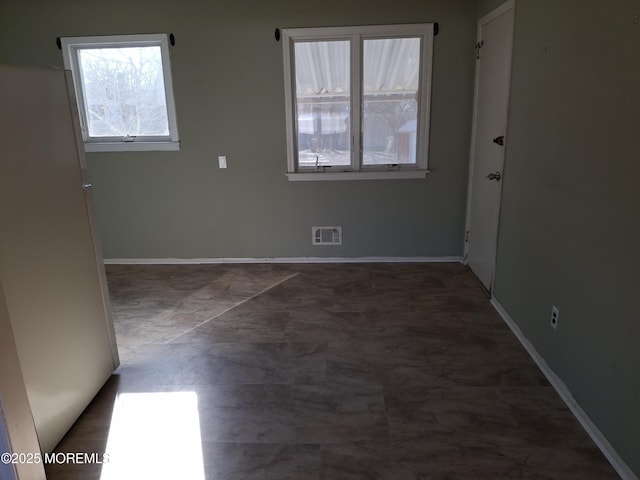 spare room with baseboards and visible vents
