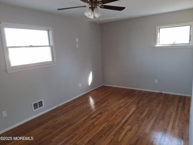 unfurnished room featuring baseboards, ceiling fan, visible vents, and wood finished floors