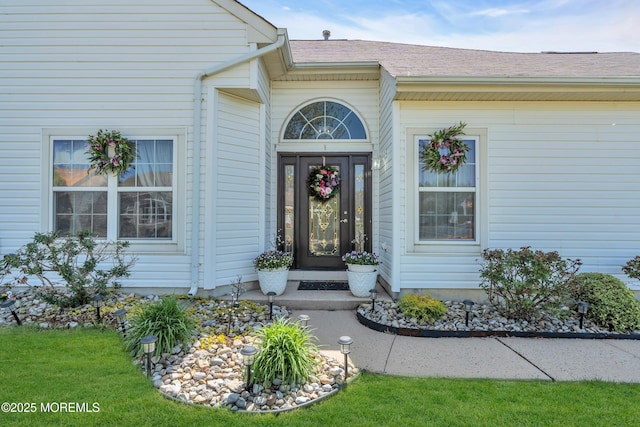 view of exterior entry with roof with shingles