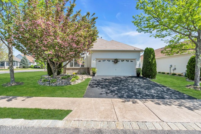 view of front of property with driveway, an attached garage, a front lawn, and brick siding