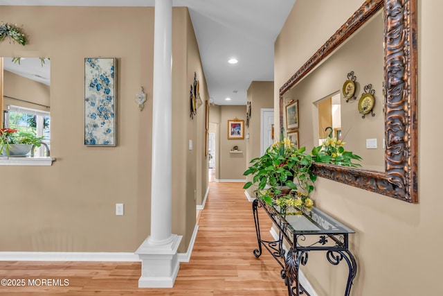 hallway with ornate columns, light wood-style flooring, baseboards, and recessed lighting