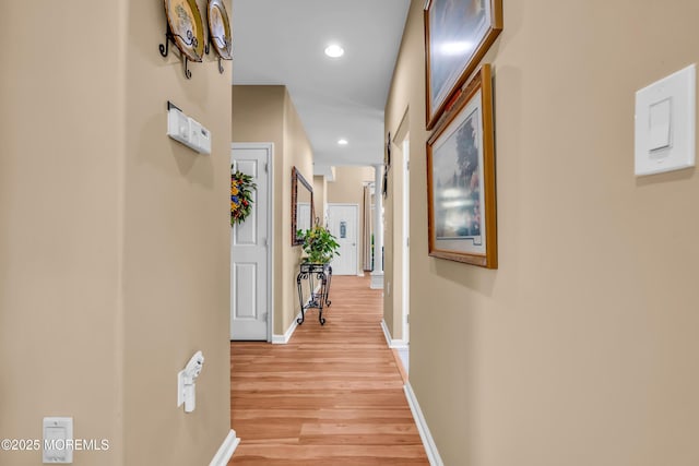 hall featuring light wood-style flooring, recessed lighting, and baseboards