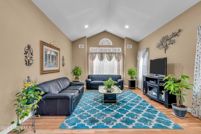 living room with wood finished floors, high vaulted ceiling, and baseboards