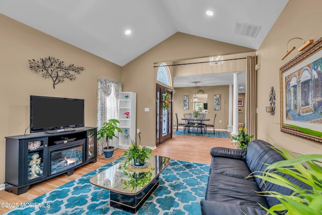living area featuring ornate columns, lofted ceiling, wood finished floors, and recessed lighting