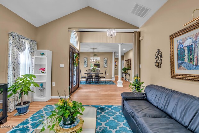 living room with decorative columns, wood finished floors, and lofted ceiling