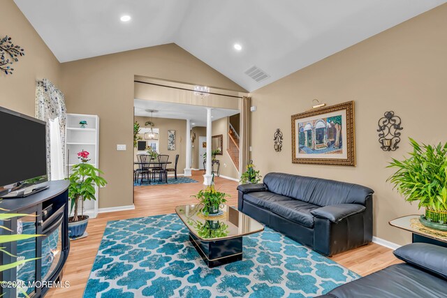 living room with vaulted ceiling, wood finished floors, and baseboards