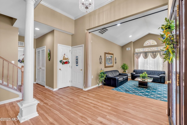 foyer featuring decorative columns, wood finished floors, baseboards, and lofted ceiling