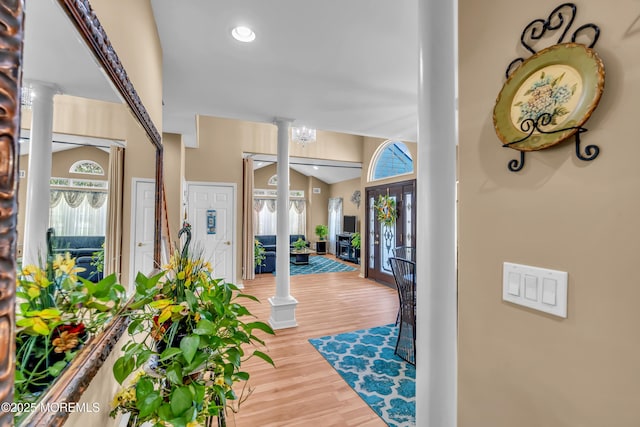 entrance foyer featuring decorative columns, wood finished floors, and vaulted ceiling