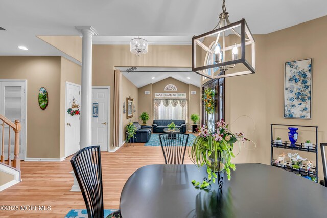 dining area with wood finished floors, lofted ceiling, decorative columns, a chandelier, and baseboards