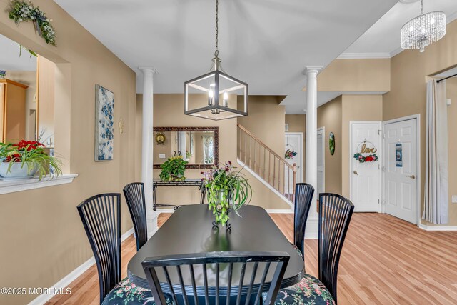 dining area featuring decorative columns, wood finished floors, baseboards, a chandelier, and stairway