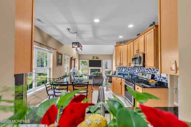 kitchen with appliances with stainless steel finishes, dark countertops, tasteful backsplash, open floor plan, and recessed lighting
