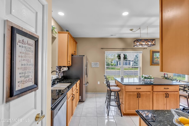 kitchen featuring dishwasher, a sink, light tile patterned floors, dark stone counters, and recessed lighting